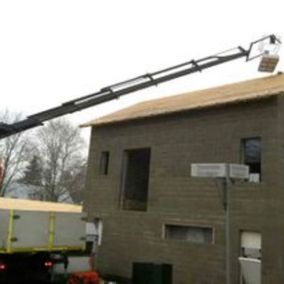 Nosturi nostaa rakennustarvikkeita rakenteilla olevan talon katolle