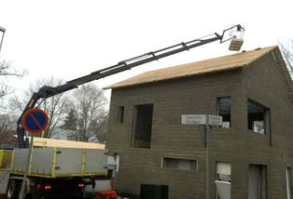 Nosturi nostaa rakennustarvikkeita rakenteilla olevan talon katolle