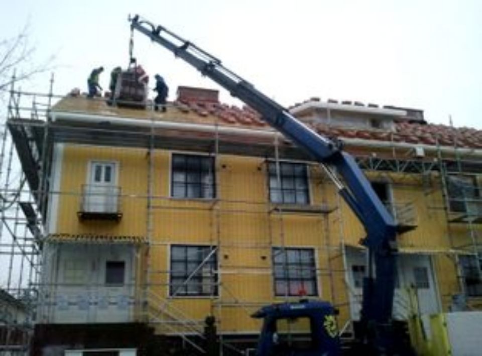 Nosturi nostaa rakennustarvikkeita saneerattavan talon katolle